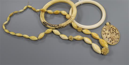 Four pieces of ivory jewellery including two bangles, a necklace and a carved pendant.